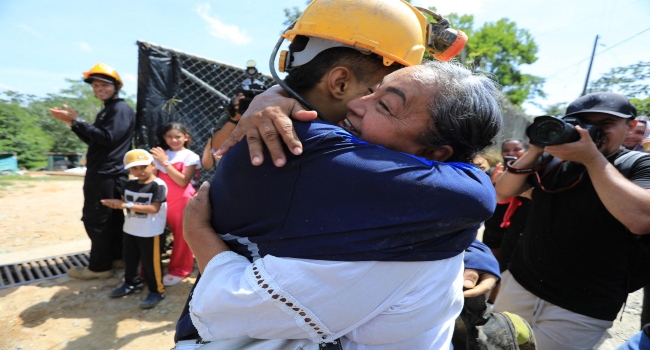 A rescued miner hugs his relative near the site where a gold mine collapsed with 23 miners trapped in Segovia, in Antioquia department, Colombia, on September 24, 2025. (Photo by JAIME SALDARRIAGA / AFP)